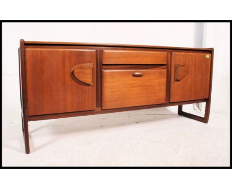 A vintage teak mid century sideboard beign raised on banded leg frames with two side cupboards, central drawer with drop down