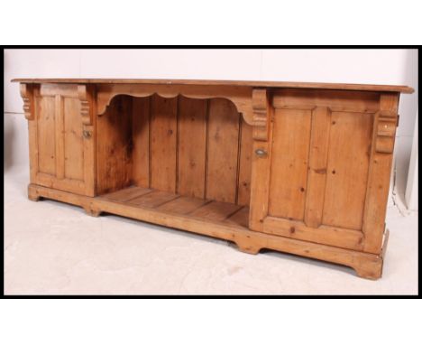 A Victorian pine low dresser base comprising end cupboards with central open recess shelf finished with flared edge top above