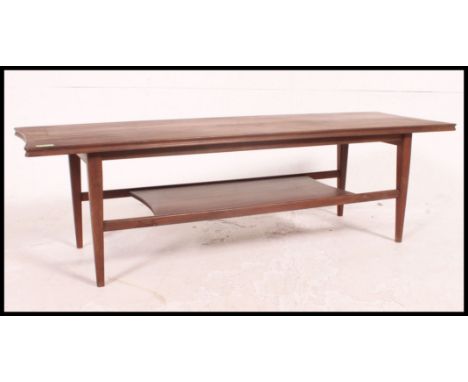 A vintage / retro 1970's Danish Influence solid teak coffee table raised on shaped  legs with magazine rack to the underside 