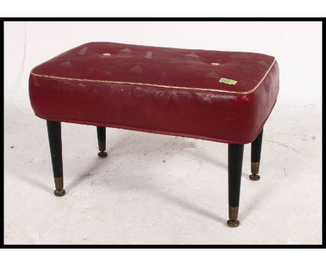 A vintage mid century dressing table stool / pouffe having a red vinyl button back pad being raised on ebonised tapered legs.