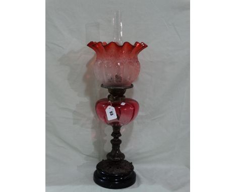 A Circular Based Oil Lamp With Cranberry Tinted Reservoir And Etched Shade