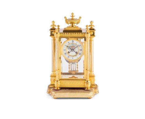 FRENCH GILT METAL MANTEL CLOCK  19TH CENTURY  the four-column glazed case surmounted by an urn finial and raised on toupie fe