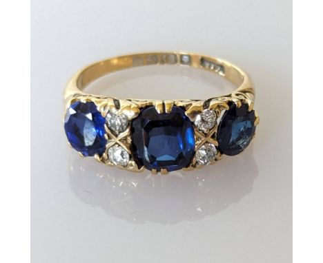 An Edwardian sapphire and diamond ring on an 18ct gold setting, the largest cushion-cut graduated sapphire measuring 8 x 8mm,