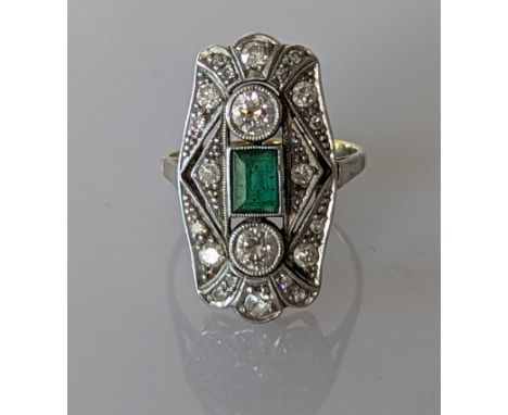 An Art Deco emerald and diamond cocktail ring in white and yellow metal, the emerald 5 x 4mm, the two largest round-cut diamo