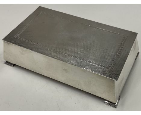 A large engine turned silver cigar box on feet. Birmingham 1958. By Adie Brothers. Approx. 606 grams. Est. £300 - £500.