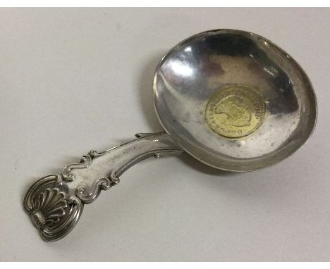 A Georgian silver caddy spoon with Spanish Charles III 774 coin. Approx. 17 grams. Est. £30 - £40.