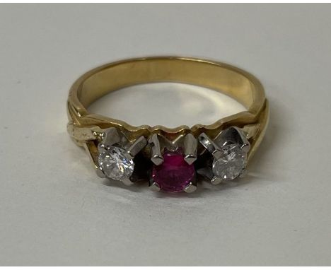 An 18 carat ruby and diamond three stone ring in two colour gold. Approx. 5 grams. Est. £150 - £200.