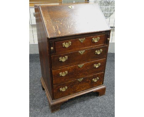 A NARROW ANTIQUE OAK BUREAU with four graduated drawers, brass furnished, pigeon-hole interior & over bracket feet, 99cms hig
