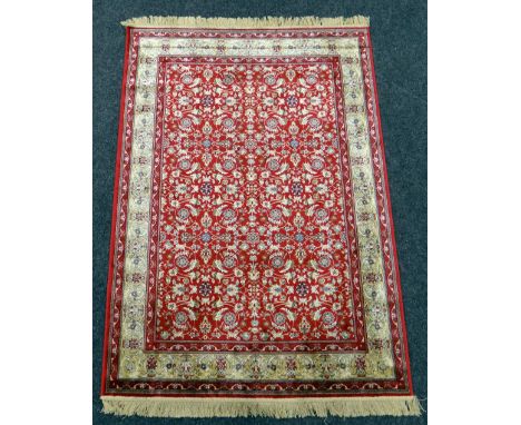 RED GROUND KASHMIR RUG with all over floral design with gold boarder, 136 x 194cms