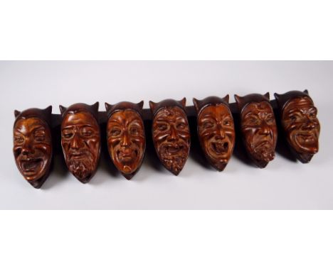 AN UNUSUAL CONTINENTAL CARVED TREEN MOUNTED STICK-STAND in the form of a series of horned Satanic faces each with a different