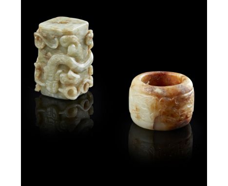 TWO CARVED JADE ORNAMENTSQING DYNASTY OR EARLIER the first a celadon and russet jade archer's ring, the exterior carved in lo