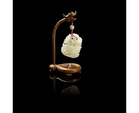 CELADON JADE PENDANTcarved and pierced to depict a heron perched on a large lotus leaf, clasping a lotus pod in its beak and 