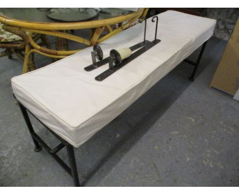 A wrought steel bench with a cream fabric cushion, 21 h x 55 w