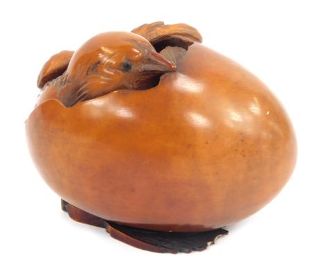 A carved wooden Netsuke depicting a chick breaking free from an egg, signed, 5cm high.