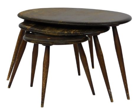 A nest of three Ercol dark elm pebble occasional tables, with a curved oval top, raised on turned legs, largest table 64cm wi