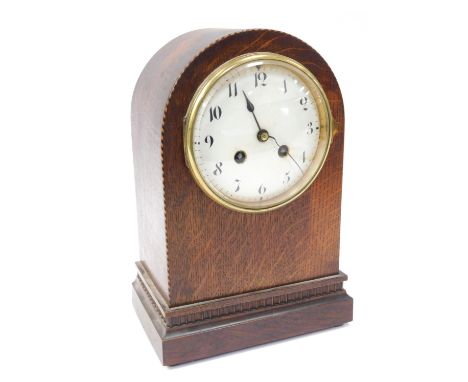 An early 20thC oak cased mantel clock, the circular white enamel dial bearing Arabic numerals, eight day movement, French wit