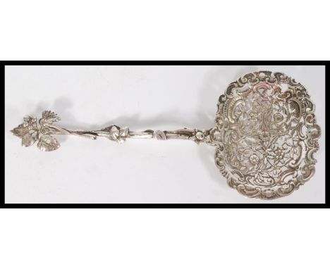 A continental silver stamped 800 large ornate sifting / caddy spoon with scrolled pierced bowl having floral decoration. Leaf