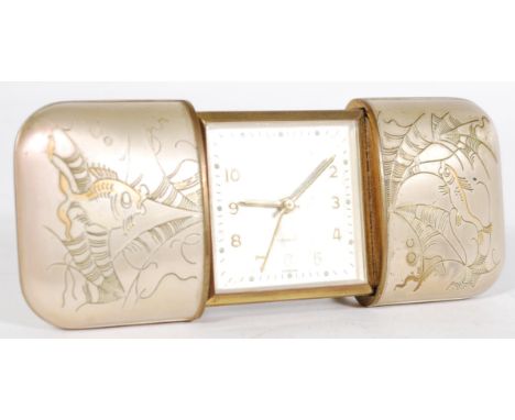 A vintage 20th century sliding pull out desk top alarm travelling clock by Europa in white metal case with engraved fish desi