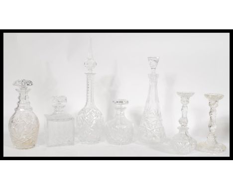 A collection of cut glass crystal decanters and candlesticks to include a tall decanter with an unusual finial lid and a pair