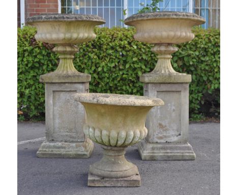 A collection of three outdoor vintage 20th century composite reconstituted stone Campana garden urns and plinths. Square plin