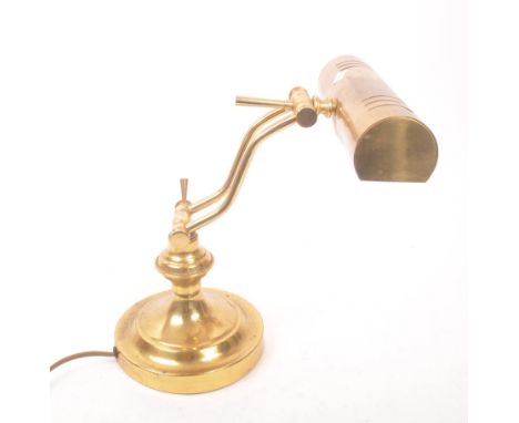 A 20th century brass bankers lamp. The lamp raised on a circular stepped pedestal base, having twin adjustable arms, and a cy