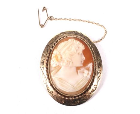 A vintage 9ct gold and shell cameo oval brooch. The cameo depicting an unknown female profile facing right with flowers on he
