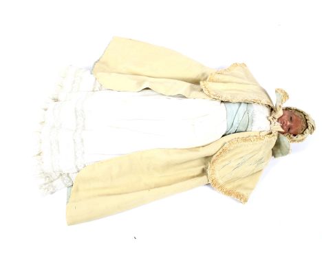 A 19th century wax headed doll. With stuffed body and wax limbs, dressed in a christening robe with a blue satin belt and coa