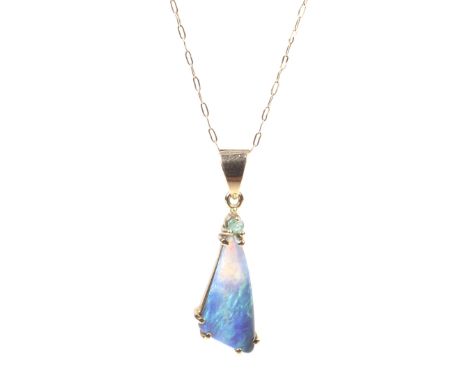 An Australian opal and emerald pendant and chain. The pendant set with a triangular cabochon semi-black opal displaying a ple