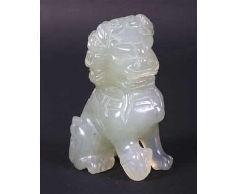 A 20th century Chinese carved pale celadon jade seated Dog of Fo. Modelled seated on its haunches with its front right paw ra