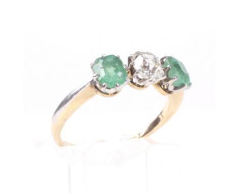 An early 20th century gold, emerald and diamond three stone ring. Centred with a cushion-shaped old-cut diamond approx.0.55ct