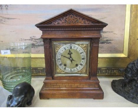 An Edwardian oak mantle clock of architectural form, having a square brass dial flanked by a column, raised on brick and plin