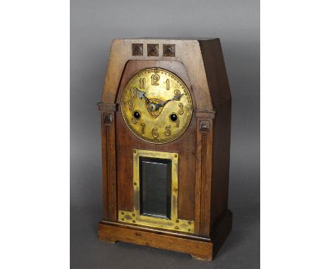 An early 20th Century walnut and brass mantel clock of Arts & Crafts architectural design, with carved motifs and bevelled gl