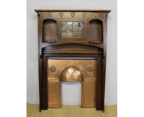 A fine Edwardian oak fire surround of Arts & Crafts design by Waring and Gillow, of angled shape, frieze set with copper leaf