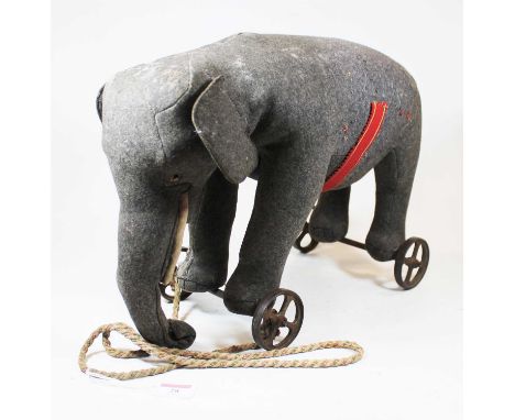 An early 20th century Steiff pull-along elephant, in grey felt, with glass eyes and button to ear, on iron four-spoke wheels,