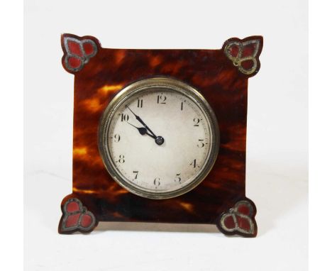 An early 20th century tortoise shell framed travel clock of square form, the proud corners inlaid with white metal and enamel