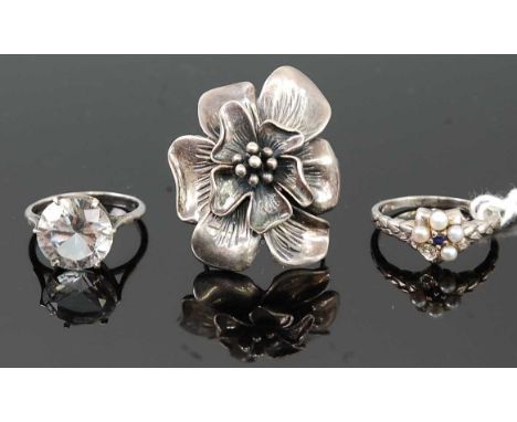 A silver and seed pearl set flower head dress ring (one stone missing); together with a silver paste set ring; and a large si