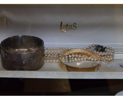 A Lotus simulated pearl necklace, a modern silver bangle and a gold plated bangle. (3)