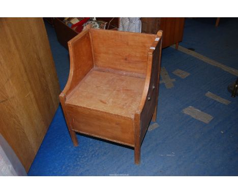 A pine chair/commode with an under-seat compartment.