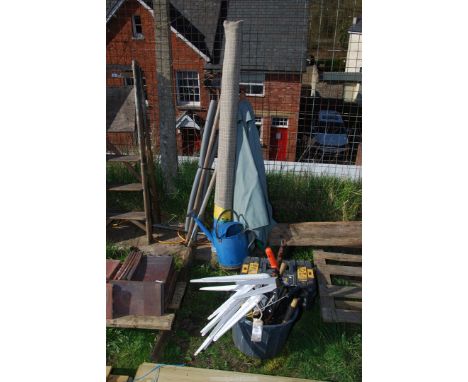 A windbreak, parasol, galvanised watering can with rose, bucket of tools etc.