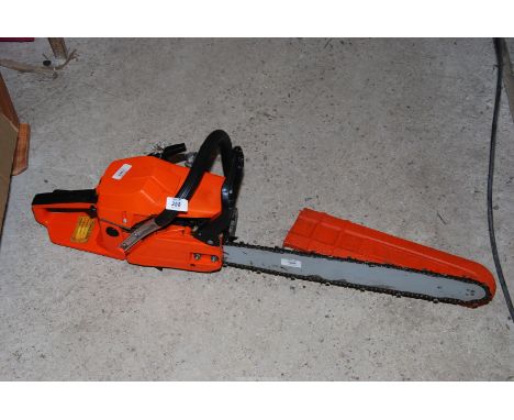 A orange heavy duty petrol chainsaw having a long cutter bar, [working at the time of lotting].