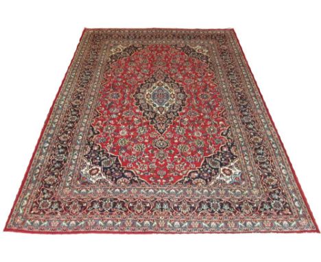 KASHAN CARPET, 331cm x 246cm, pendant medallion with scrolling vines on a rouge field within spandrels, bands and correspondi