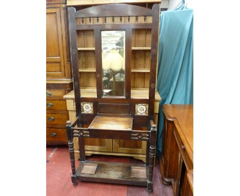 AN EDWARDIAN MAHOGANY MIRRORED HALLSTAND, the galleried top over a central bevelled mirror and twin decorative tiles, lower l