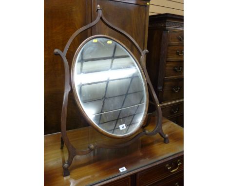 A REGENCY MAHOGANY DRESSING MIRROR of oval form in a shaped open stand with turned roundels and acorn finial, 89 x 63 cms