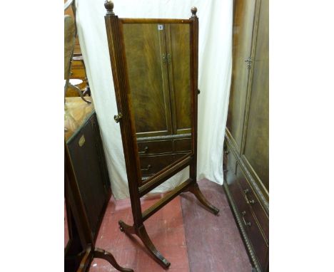 A REGENCY MAHOGANY CHEVAL MIRROR, rectangular with cushion veneer and turned finials on reeded column supports with brass tig
