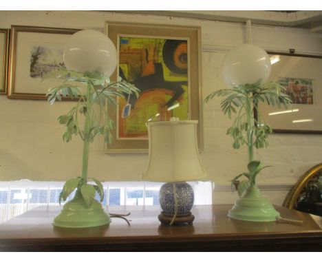 Two green painted metal table lamps in the form of a plant with white glass shades, and a Chinese blue and white lamp base wi