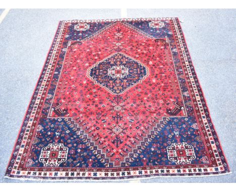 A Kashgai carpet with a central medallion, geometric animals, birds and flowers on a red ground, 275cm x 218cm 