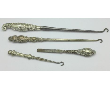 Three silver handled button hooks and a silver nail file