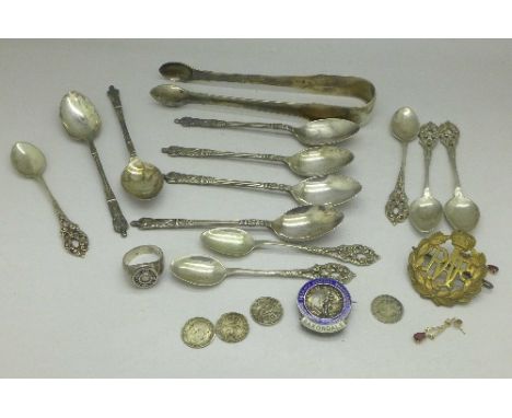 A pair of silver sugar bows, six 800 silver spoons, a silver Paul Smith ring, a silver and enamel badge and six plated spoons