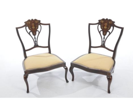 A pair of Edwardian mahogany low seat chairs,
each with an openwork back centred with a shaped panel inlaid with urns, masks,