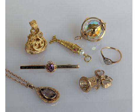 A yellow gold pierced gem-set fob, 33mm; a faceted crystal pendant in a gold frame; a ribbon bell brooch; a gold fish charm w